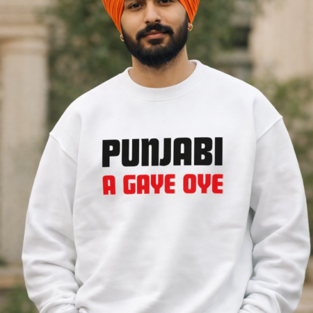 “A young Indian man with a neatly tied orange turban and trimmed beard stands outdoors wearing a white sweatshirt that reads ‘PUNJABI’ in bold black letters and ‘A GAYE OYE’ in bold red letters. He looks confidently at the camera with his hands in his pockets.”